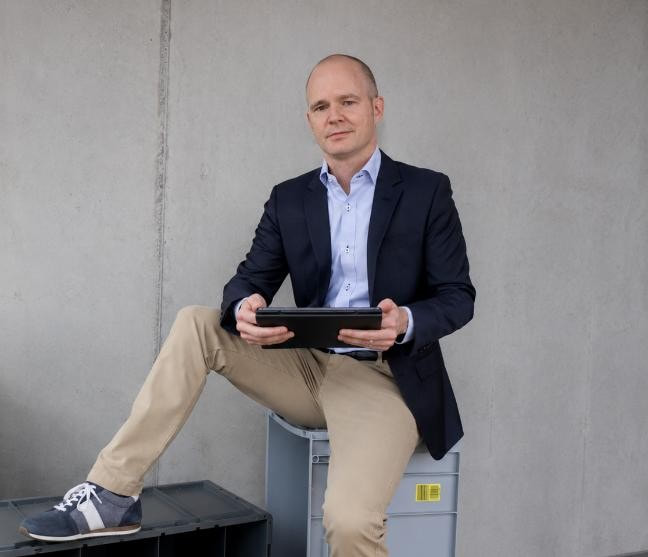Ein Person sitzend auf Behälter und einem Tablet in der Hand
